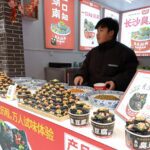 A street vendor with piles of Black Stinky Tofu on a counter.