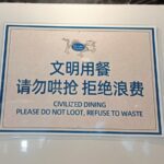 A restaurant sign written in Chinese and English saying 'Civilized dining Please do not loot, refuse to waste.'