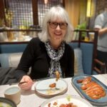 Tracey Gemmell seated in a Beijing restaurant eating Peking duck.