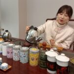 Lady pours tea in a Chinese tea room, with decorated pots.